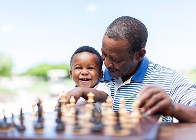 Man and child smiling playing chess