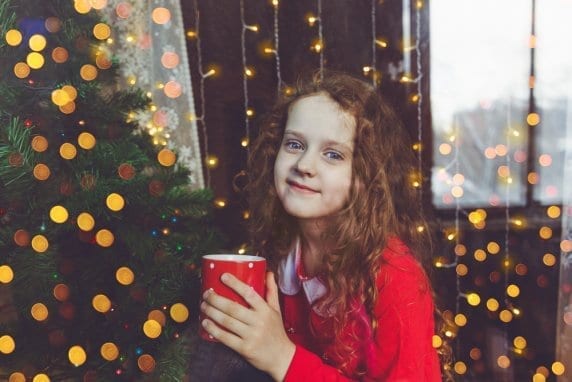 girl standing in front of christmas tree