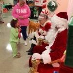 One of our KKids excitedly meets Santa and Mrs. Claus, volunteer Ruthie Coleman.